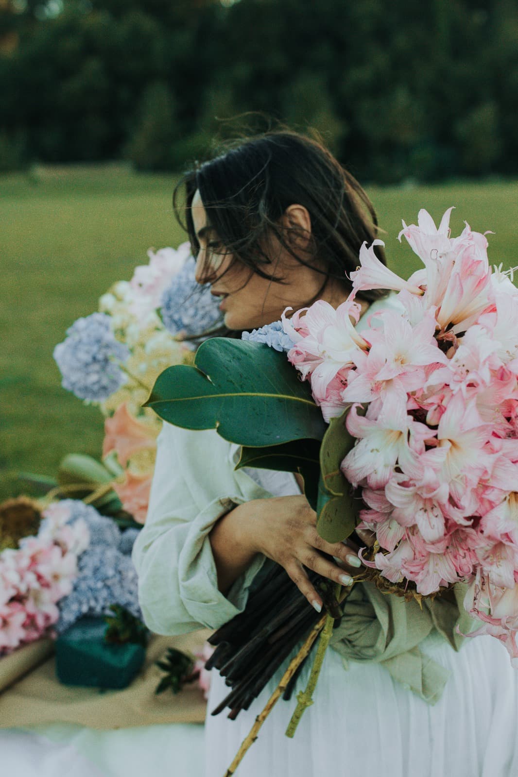 Person arranging a blush and cream floral bouquet at an outdoor table