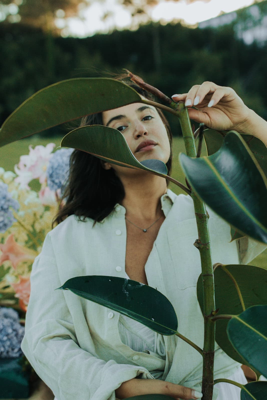 Close, editorial portrait of a person behind a large green leaf