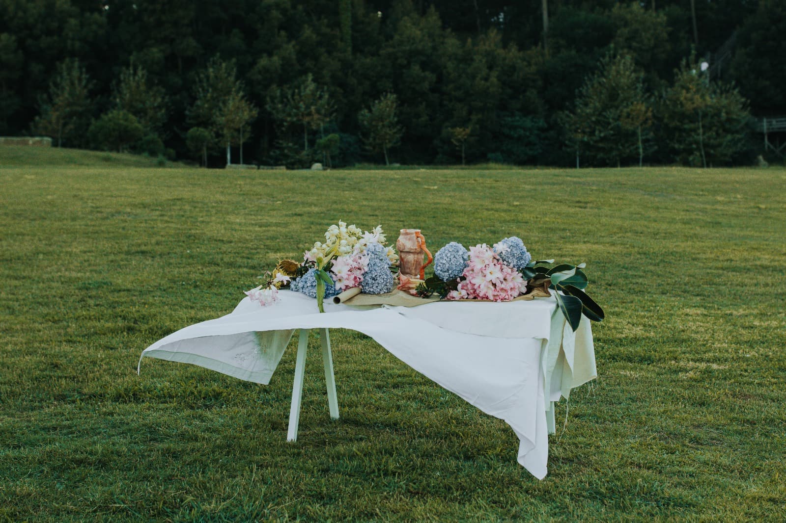 Outdoor event table styled with blue hydrangea and blush flowers, golden hour